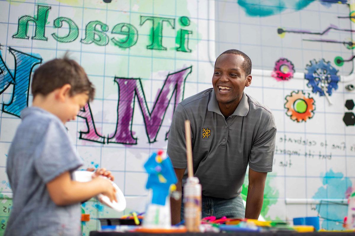 Man smiling at younger child working on project