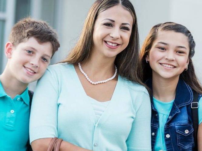 Woman and younger children are standing together smiling for the picture