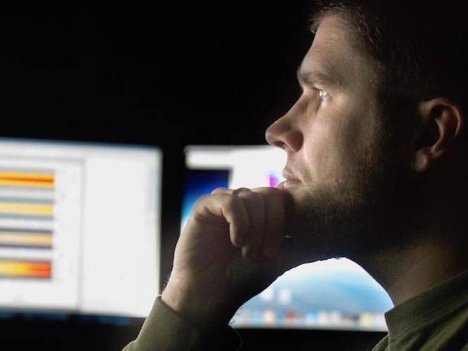 Man looking at computer monitors with charts on them