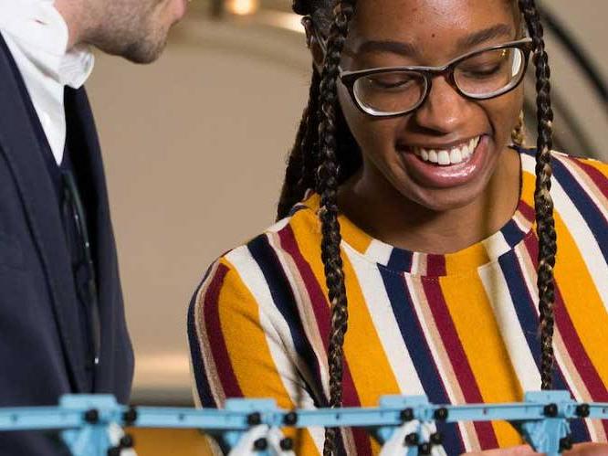 Woman is smiling and looking down at her project