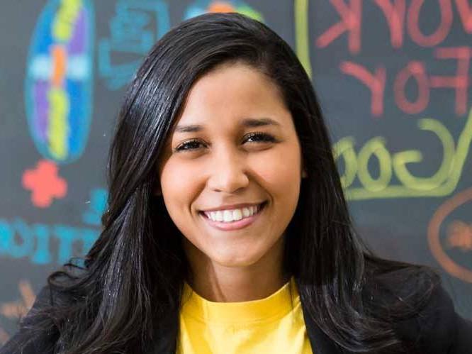 Business woman smiling for a picture infront of a colorful chalk board